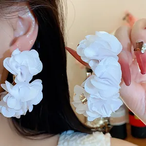 Detailed view of elegant white chiffon fabric flower C-shaped earrings with silver needles