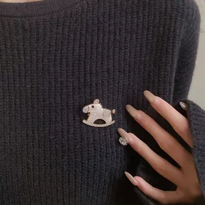 Detail shot of an elegant rocking horse brooch with rhinestones on a black sweater.