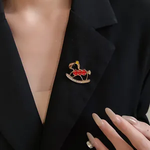 Detailed view of a vintage rocking horse brooch with red enamel and rhinestones on a blazer