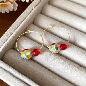 Macro view of colorful resin bead hoop earrings with orange polka dots in a tray