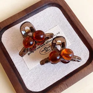 Pair of vintage Maillard brown acrylic mini hair claws with amber bead design.