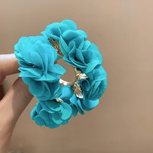 Close-up of teal chiffon flower C-shaped earrings featuring delicate gold leaf accents