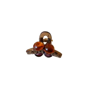 Mini amber acrylic hair claw clip with round decorative beads on white background