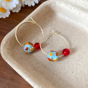 Detailed macro shot of summer resin hoop earrings with colorful beads in a natural tray