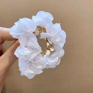 Close-up of white chiffon flower C-shaped earrings with gold ginkgo leaf accents