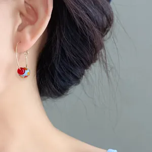 Close-up detail of colorful resin bead hoop earrings on a model's ear for a summer look.