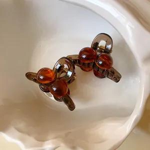 Macro view of two Maillard style amber acrylic mini round hair clips in a white dish