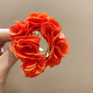 Close-up detail showing the vibrant orange chiffon fabric flowers of the C-shaped earring