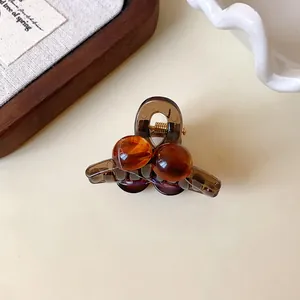 Detail view of a vintage brown acrylic mini hair claw clip with two round beads