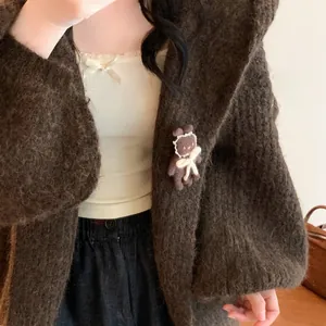 Close-up of a cute brown flocked bear brooch with a bow pinned to a soft mohair cardigan