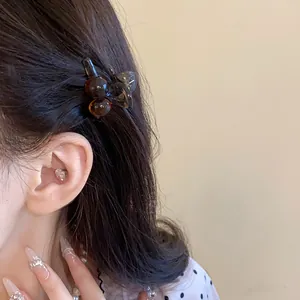 Detailed view of a Maillard brown acrylic mini hair claw clip used to style dark hair