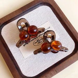 Macro view of two mini amber acrylic hair claw clips with a vintage circular design.