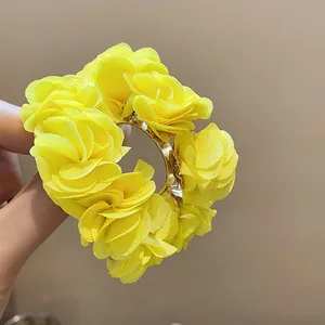 Detailed close-up of yellow chiffon flower C-shaped hoop earrings for a trendy vacation look