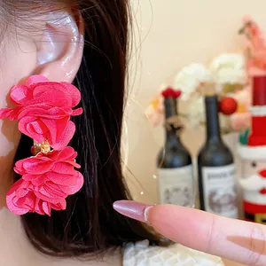 Close-up of vibrant red chiffon flower C-shaped earrings elegantly worn on the model ear