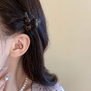 Detail view of a Maillard brown acrylic mini round hair claw worn in dark hair