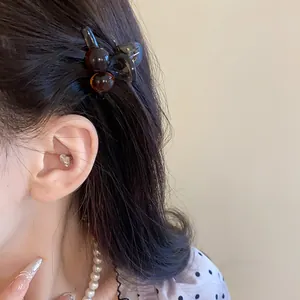Detailed close-up of a retro amber acrylic mini hair claw clip worn on side hair