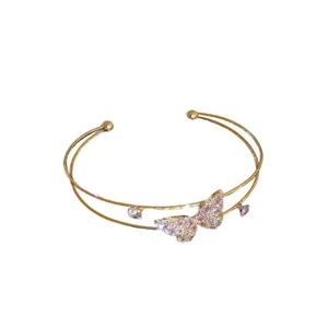 Elegant double-layered gold cuff bracelet featuring a sparkling crystal butterfly charm