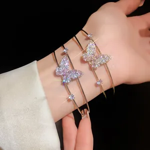 Close-up of elegant sparkling zircon butterfly double-layered open bangles on a woman's wrist.