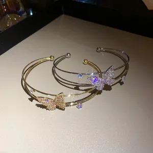Close-up of sparkling zircon butterfly double-layered cuff bracelets in gold and silver