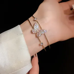 Close-up of elegant double-layered gold bangle with sparkling pink butterfly charm