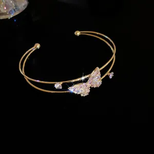 Detail view of a double-layered gold bangle with a shimmering zircon butterfly motif.
