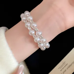 Detail view of double-layer pearl bracelet with square rhinestones on wrist