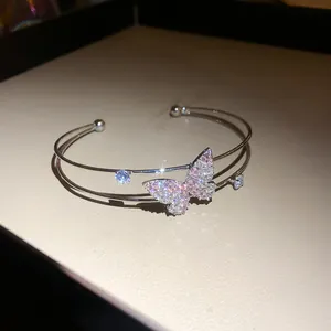 Detailed close-up of double-layer silver cuff bracelet with pink crystal butterfly