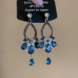Macro detail of elegant silver needle drop earrings with blue and white crystals