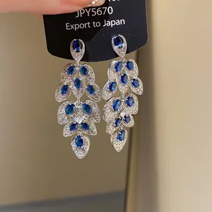 Close-up of elegant silver-tone tassel earrings with blue marquise crystals and clear pavé