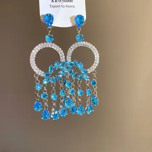 Detailed macro view of luxury silver tassel earrings featuring blue teardrop stones