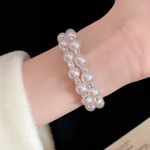Elegant double-layered pearl bracelet with shimmering rhinestone spacers on wrist.