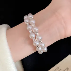 Close-up detail of a double-layered pearl bracelet with rhinestone accents