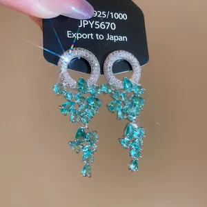 Close-up of sparkling teardrop floral tassel earrings with blue stones and crystals