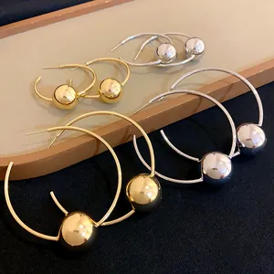 Detail view of gold and silver hoop earrings with metallic ball accents