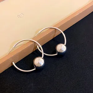 Minimalist round silver hoop earrings with a polished metal ball charm for women