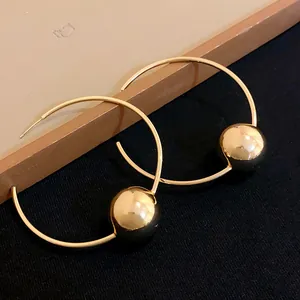 Close-up detail of stylish gold-finished hoop earrings with large metallic beads