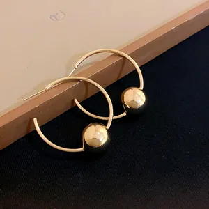 Close-up detail shot of elegant gold hoop earrings with polished metal ball bead design