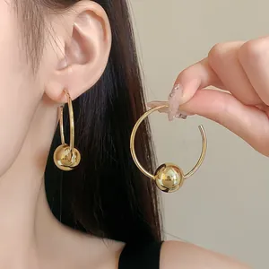 Detailed view of oversized gold hoop earrings with spherical bead on a model