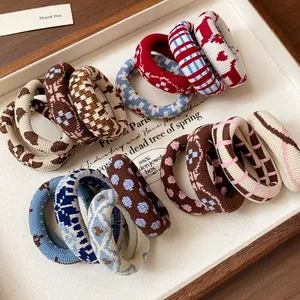 Detailed close-up view of various patterned fabric elastic hair ties in a stylish white tray