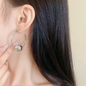 Minimalist silver hoop earring with a sliding ball bead, close-up view on a female model.