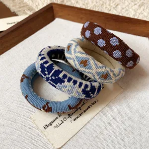 Close-up detail of four fabric printed elastic hair ties in varied blue and brown patterns