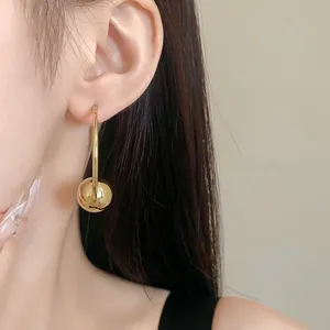 Detailed view of minimalist gold ball hoop earrings with silver needles on model