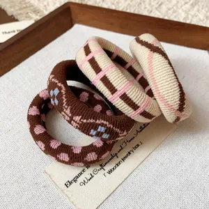 Detailed macro view of four printed fabric elastic hair ties in elegant warm tones