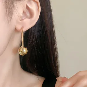 Close-up detail showing a gold hoop earring with a large metallic ball charm