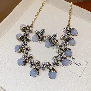 Parure de bijoux style français vintage avec perles et strass posée sur un fond beige