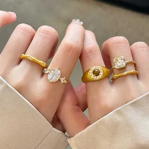 Detailed close-up view of gold-plated bamboo rings and zircon signet rings on fingers