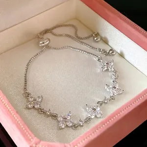 Elegant silver adjustable bracelet with flower-shaped cubic zirconia in a gift box.