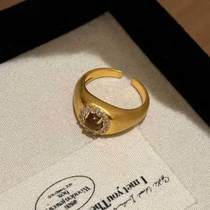 Macro detail of a vintage gold open ring featuring a central stone and zircon halo.