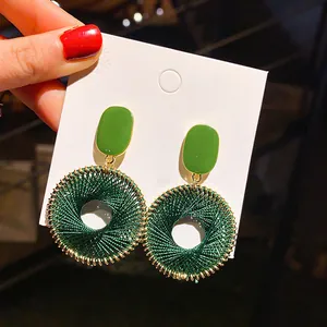 Detailed view of green enamel rectangle and dark green thread woven hoop earrings