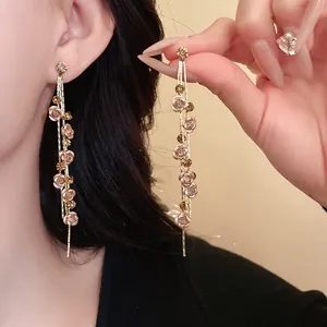 Detailed view of long gold-tone tassel earrings with pink roses and sparkling stones